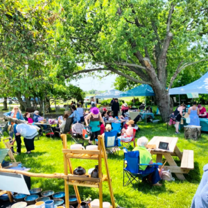 Journée mondiale du tricot 2025, un rendez-vous à la ferme. Filage, tricot et mini-marché. Plusieurs kiosques et des gens qui parlent, tricotent, découvrent. Une journée conviviale, sous les arbres.